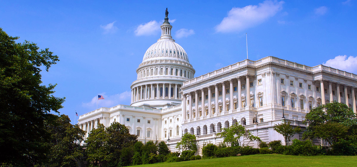 Exterior view of the U.S. Capitol with blue sky and green lawn